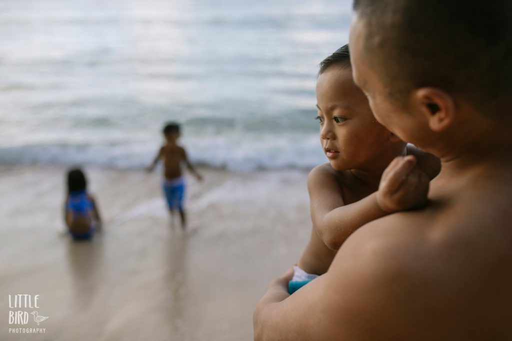 dad and kids plyaing at the beach on the north shore oahu at sunset