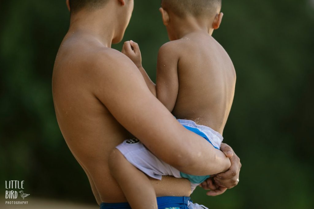 dad holding son at the beach during a family photo session