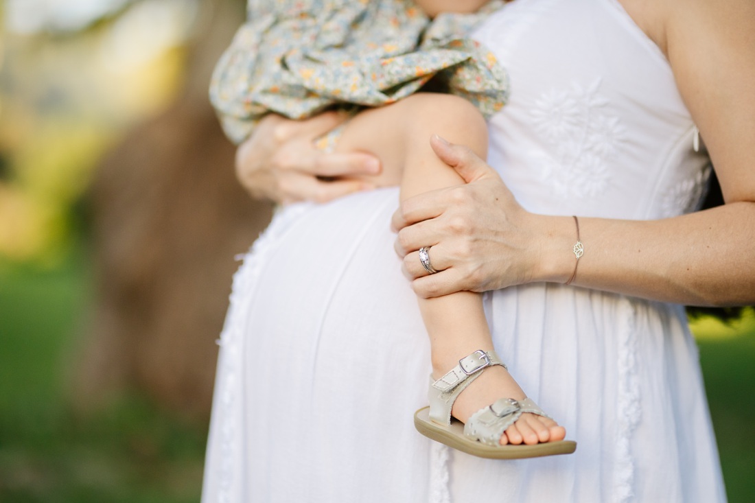 toddler perched on a pregnant belly during a maternity photo shoot in hawaii