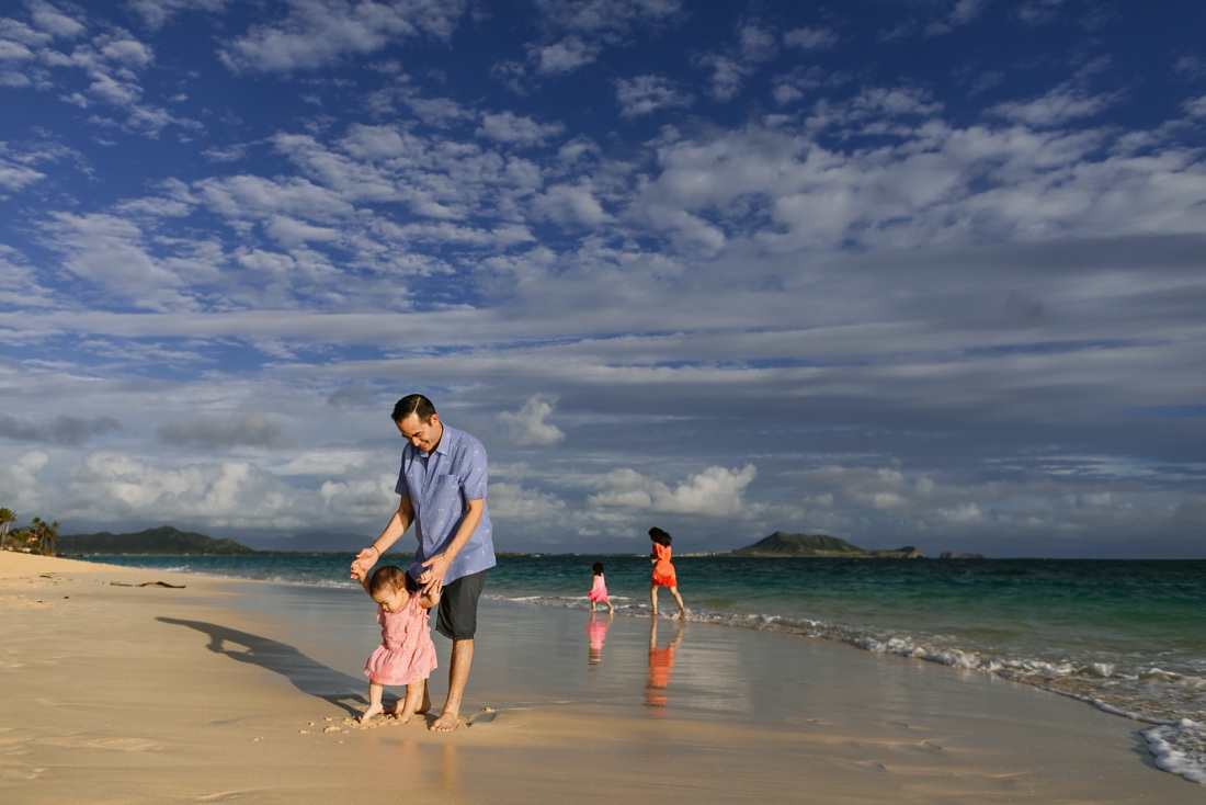 family of four plays on the beach at sunrise in hawaii